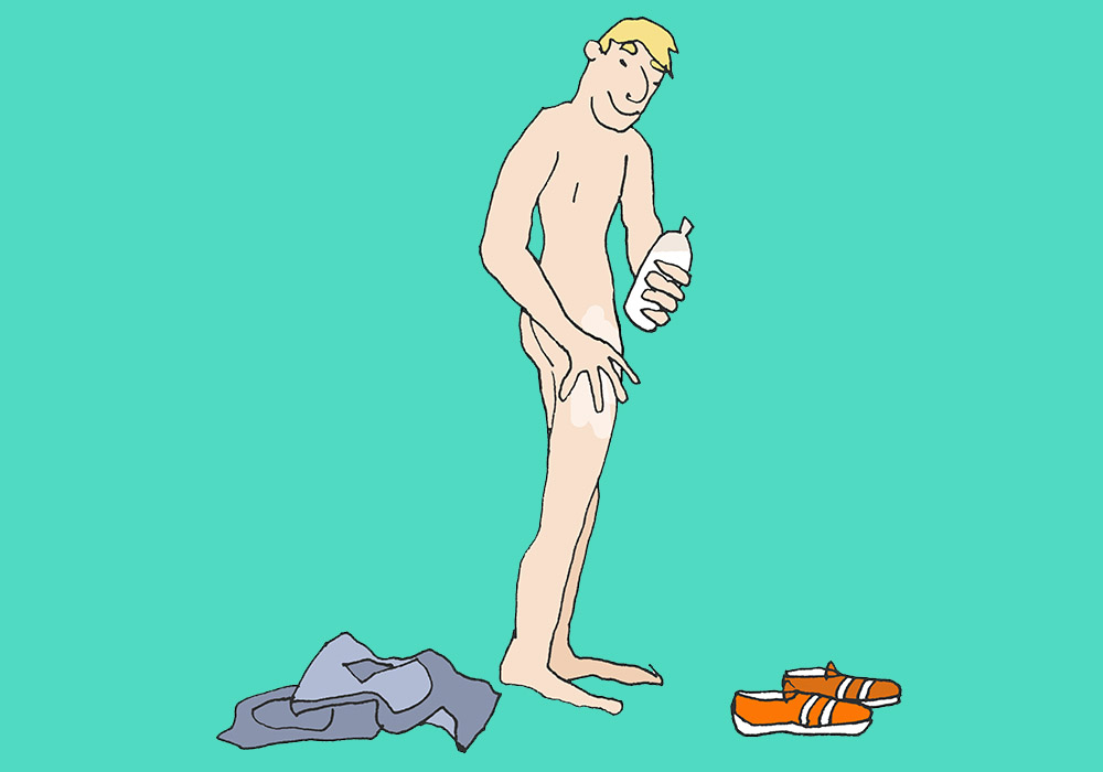 A naked man standing puts lotion on his body.